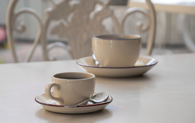 Two coffee cups stand on a table (monochrome)