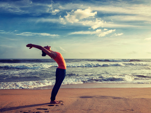 Young sporty fit woman doing yoga Sun salutation Surya Namaskar