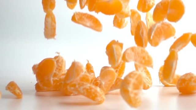 Orange or tangerine slices falling on white background. This video clip was shot in slow motion.