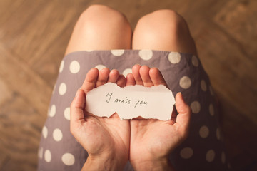 Woman holding a paper note with the text I miss you