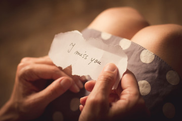 Woman holding a paper note with the text I miss you - obrazy, fototapety, plakaty