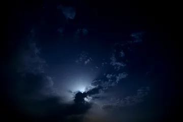 Rolgordijnen De maan achter de wolken aan de nachtelijke hemel. © olgapkurguzova
