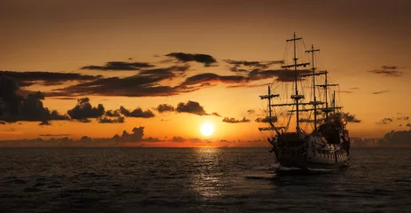 Foto op Plexiglas Schip Piratenschip op open zee bij de zonsondergang met kopieerruimte