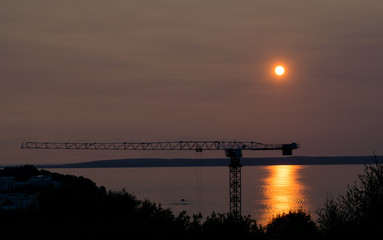 Hoisting crane on the sunset