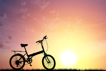 Bike silhouette on the grass.Blurred background sunset