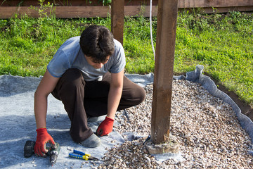 man fixes electrical cord on a wooden post