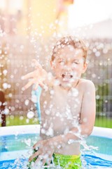 child splashing water in inflatable garden pool