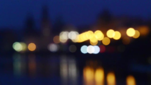 View to the Old Town in the center of Prague from Vltava river with water reflection at nght with illumination and traffic, travel blurred outdoor european background
