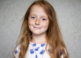 Close up portrait of a ginger smiling girl with freckles