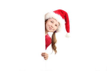 the portrait of smiling little girl on Santa Claus hat peeking by the white board looking at camera isolated on white background.