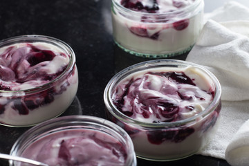 Yogurts with fruits assortment in glass bowls on dark marble background. Natural and fruit healthy, diet, gourmet dessert for granola breakfast. Sweet yoghurts closeup.