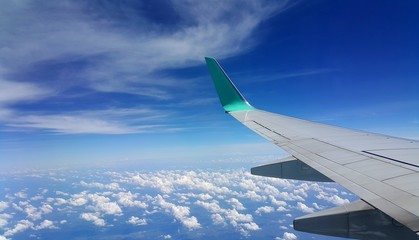 Fototapeta premium Wing of an airplane flying above the clouds. people looks at the sky from the window of the plane.
