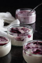 Yogurts with fruits assortment in glass bowls on dark marble background. Natural and fruit healthy, diet, gourmet dessert for granola breakfast. Sweet yoghurts closeup.