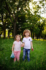 Naklejka na ściany i meble little boy and girl holding hands on the green background. brother and sister holding hands with toys
