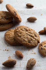 Cookies pile with chocolate chip and almond on light textile background. Delicious morning snacks for breakfast, brunch and lunch. Appetizing, healthy and fast food
