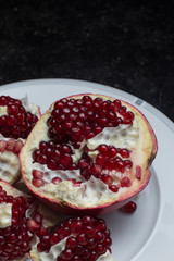 Red juicy pomegranate on dark marble background. Healthy, antioxidant, fresh, gourmet, delicious, organic fruit. Ingredient for grenadine. Close-up and copy space.