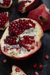 Red juicy pomegranate on dark marble background. Healthy, antioxidant, fresh, gourmet, delicious, organic fruit. Ingredient for grenadine. Close-up and copy space.