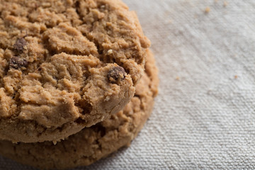 Cookies pile with chocolate chip on light textile background. Delicious morning snacks for breakfast, brunch and lunch. Appetizing, healthy, sweet, scrummy, and fast food.
