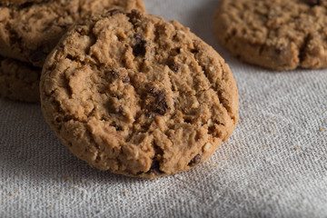 Cookies pile with chocolate chip on light textile background. Delicious morning snacks for breakfast, brunch and lunch. Appetizing, healthy, sweet, scrummy, and fast food.