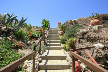 Garden design with stairs, stones and clay pots with flowers, Rhodes, Greece 