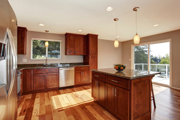 Spacious kitchen room with bar, brown cabinets and pendant lights.