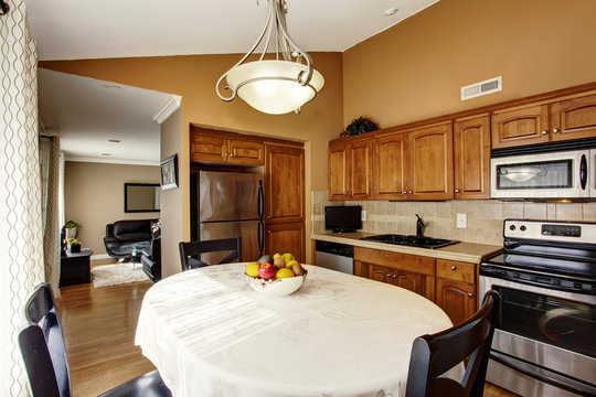 Cozy kitchen and dining room interior with black table set and brown cabinets.