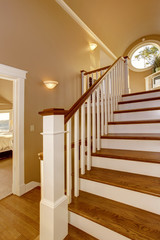 House interior. Hallway with wooden staircase and white railings.