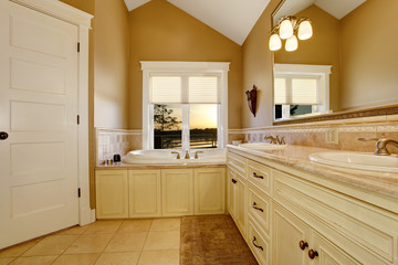 Cozy bathroom interior with old white cabinets, tile floor and vaulted ceiling.
