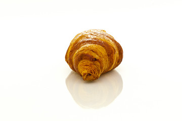 Croissant with powdered sugar with reflection on white background.