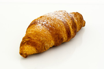 Croissant with powdered sugar on white background.