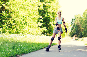 Fototapeta premium happy young woman in rollerblades riding outdoors