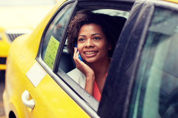 happy african woman calling on smartphone in taxi