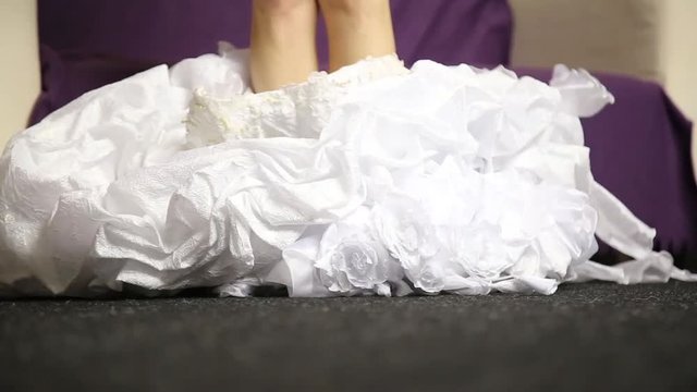 young bride comes to couch, undressing wedding dress. close up legs