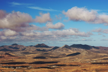 View on desert hills on hot summer sunny day and blue sky with clouds. Shadows from clouds on earth