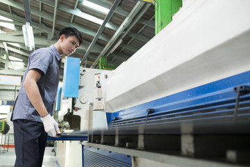 Man controlling hydraulic press machine for cutting steel.