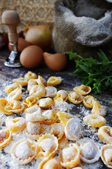 Homemade pasta ravioli on old wooden table with flour, eggs, kit