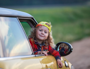 Happy little kid looking out from the yellow car