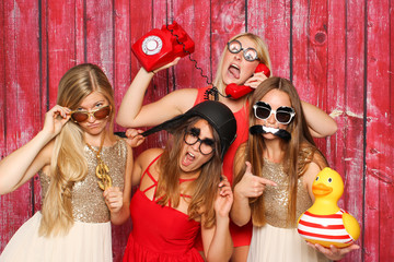Photo Booth Party mit lustigen Probs - Junge Mädchen albern vor Fotobox herum  - obrazy, fototapety, plakaty