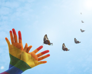 Multi-colour rainbow flag color pattern overlay on human people hand in butterfly shape upwards...