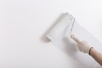 Close up of painter hand painting a wall grey with paint roller