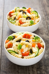 Pasta salad in a bowl on a rustic wooden table

