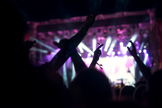 Photo of a crowd, happy people enjoying rock concert, raised up hands and clapping of pleasure, active night life concept.