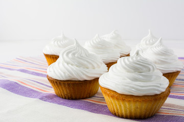 White cupcakes on the striped  linen napkin close up