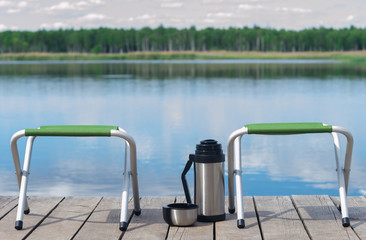 two vacant seats on the pier and hot tea waiting for guests