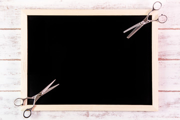 Blank blackboard and scissors hairdresser on wooden table.Templa