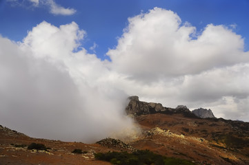 low clouds, crawling on the ground level in the mountains. Sunlight falling on the land plots. Sunny day. The mountainous part of the island of Socotra. Yemen
