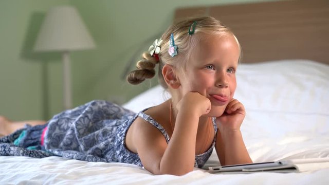 little cute girl plays a game on the tablet