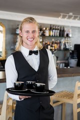 Waiter holding a tray with coffee cups in restaurant