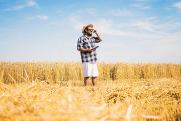 Naklejka na ściany i meble Man on a wheat field holding a tablet.