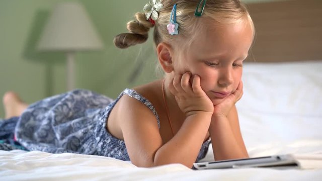 little cute girl plays a game on the tablet